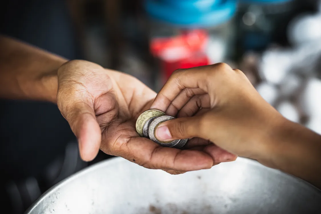 Close-up of a Filipino hand receiving coins, illustrating daily cash transactions and the real-world impact of cost of living in the Philippines.