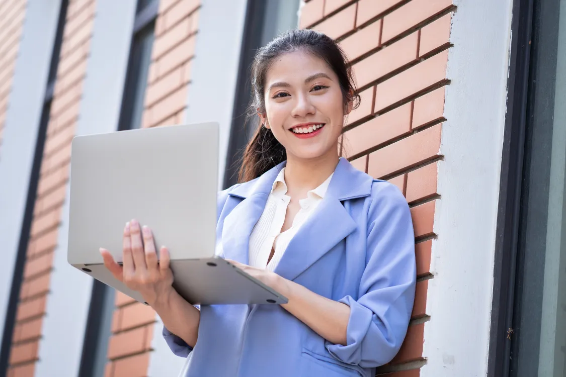 Smiling Filipino accounting virtual assistant holding a laptop, ready for remote bookkeeping support.