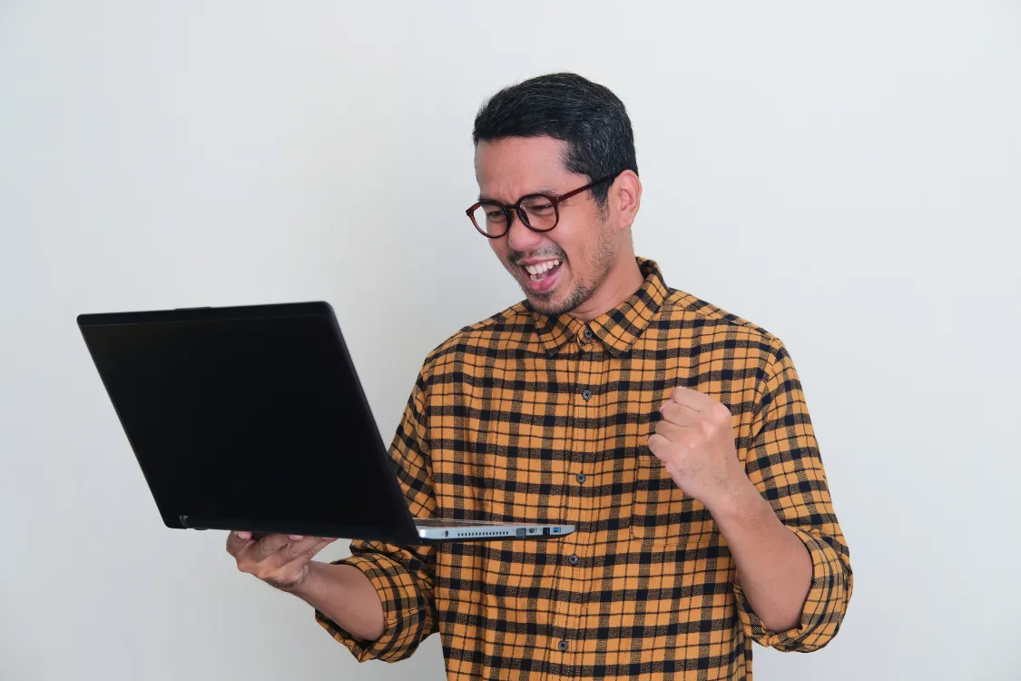A Filipino male celebrating a successful remote interview on his laptop.