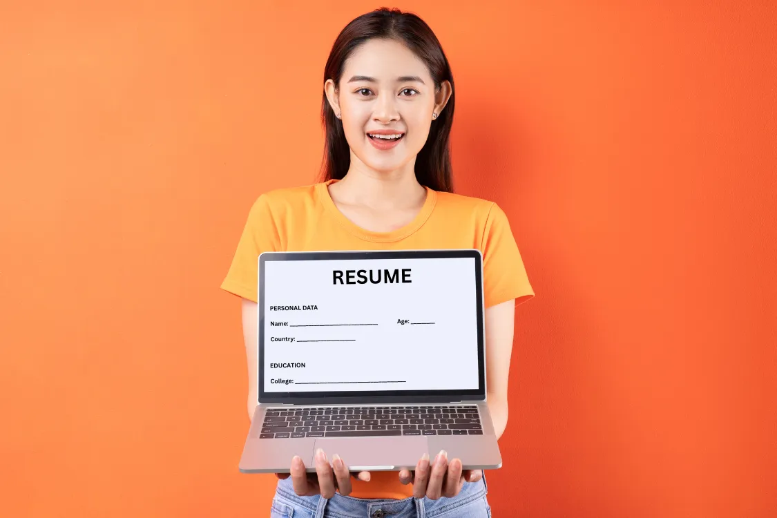 Young Filipino woman presenting a digital resume on her laptop against an orange background