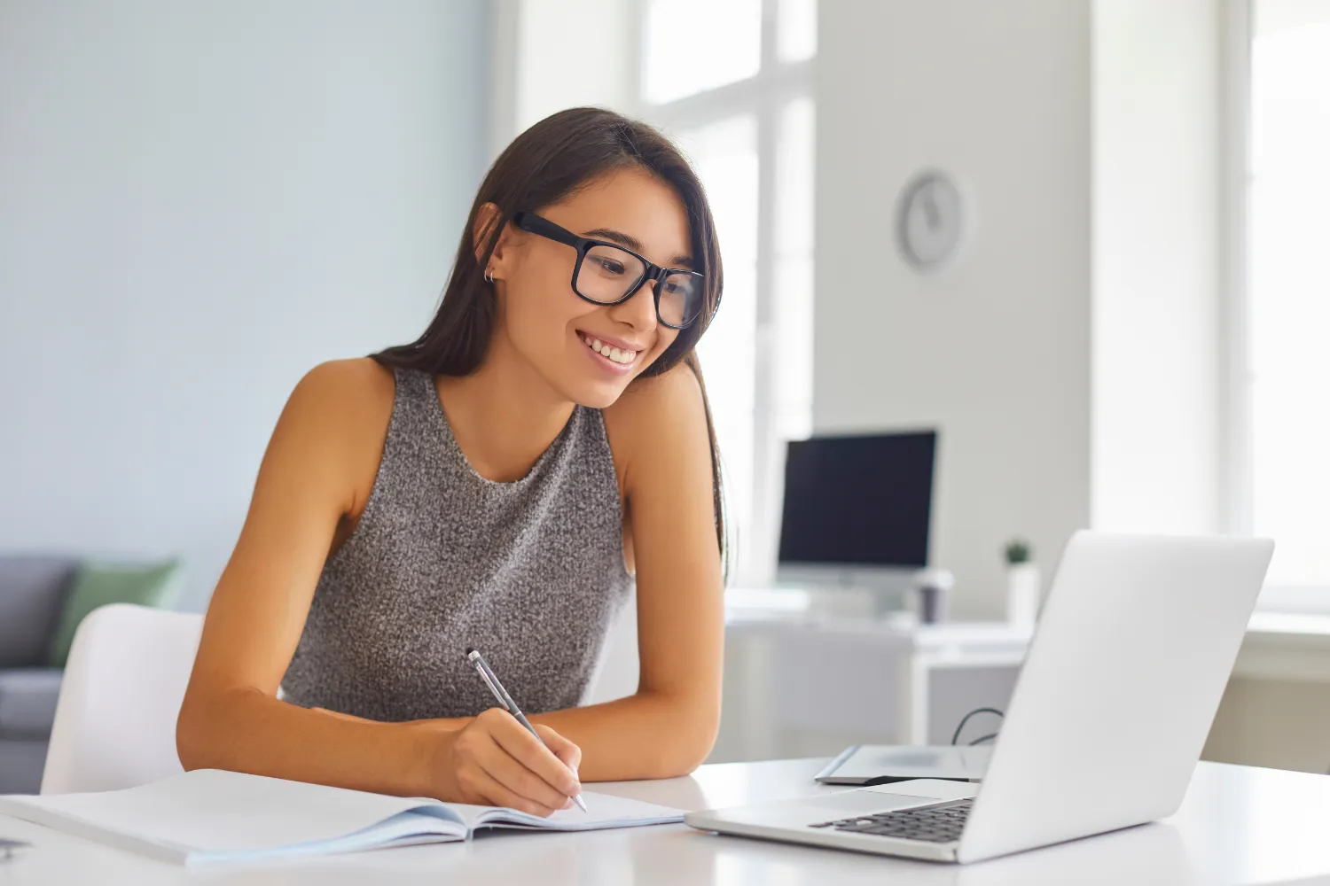 A Filipina remote worker working on her laptop while smiling.