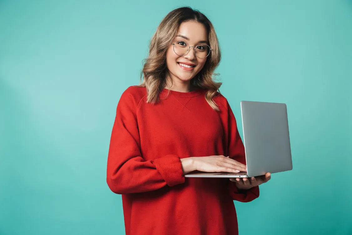 Filipino woman holding a laptop and smiling, ready for remote tech interview or job application