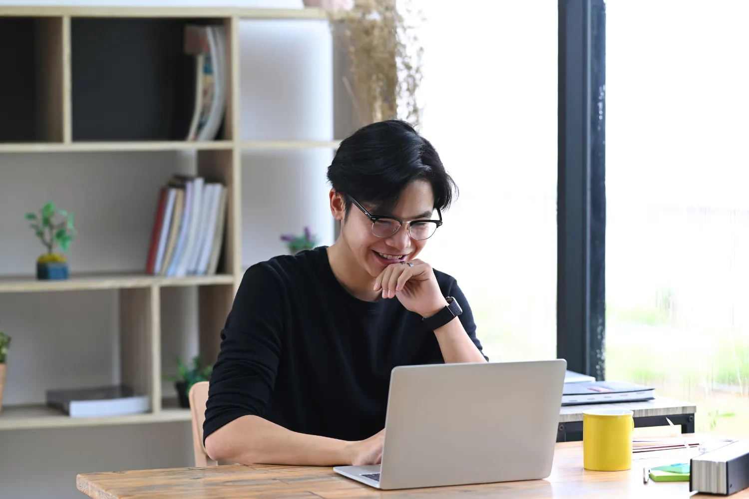 Remote employee smiling while working on his laptop.