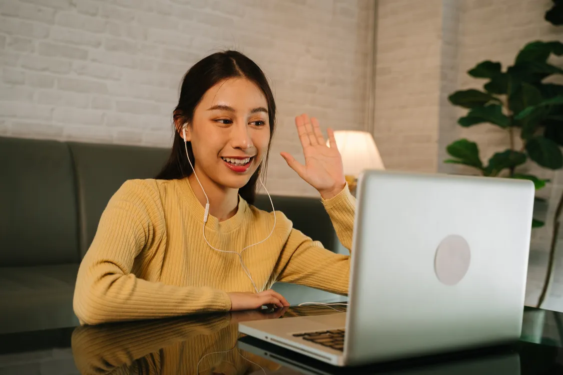 Filipino woman smiling and waving on a video call during a remote job interview