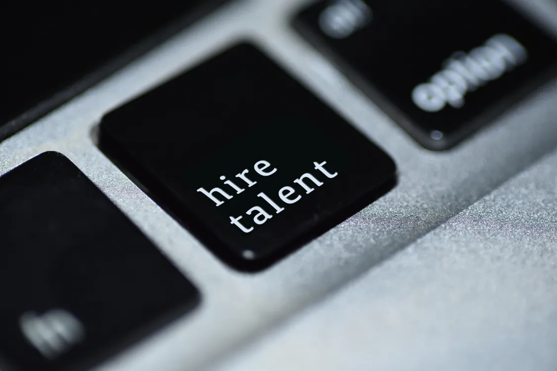 Close-up of a keyboard with a black key labeled "hire talent" representing digital recruitment and talent acquisition