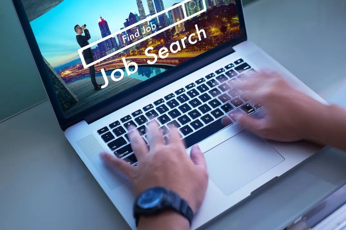 Hands typing on a laptop with a job search interface on screen, symbolizing the process of finding and hiring virtual assistants online.