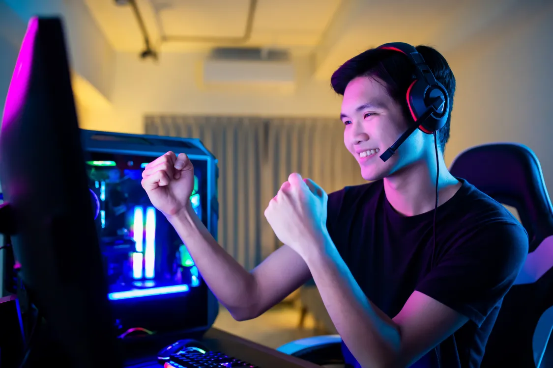 Man with headset celebrating a win during a virtual game on his computer