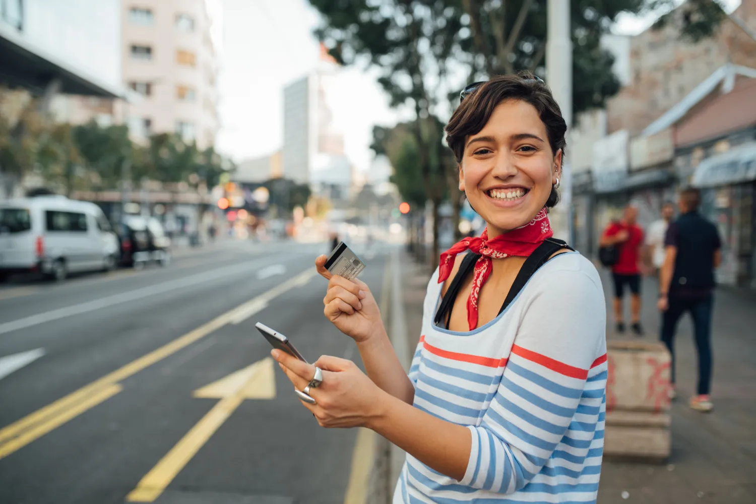 Woman holding card and checking phone for pay.