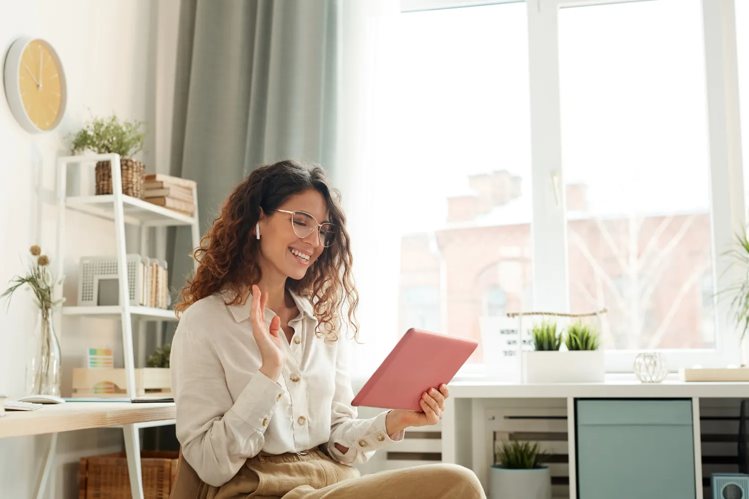 An employer waving hello to an interview via video call on her tablet.