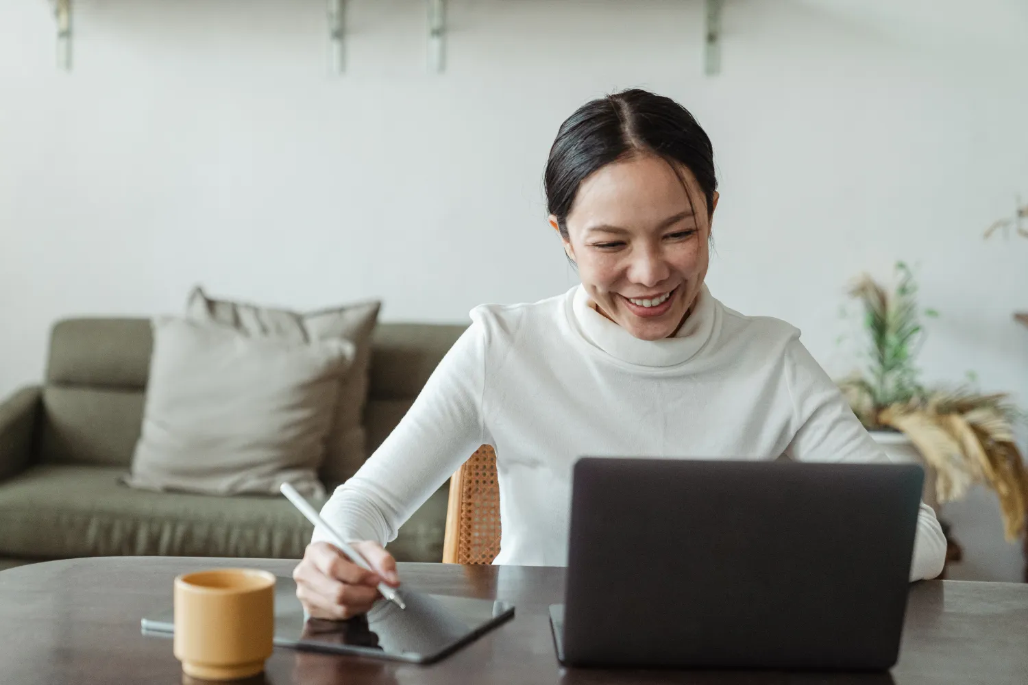 Woman watching on her laptop while taking notes.