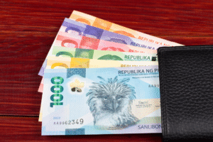 Colorful Philippine peso bills partially inside a black leather wallet on a wooden surface.