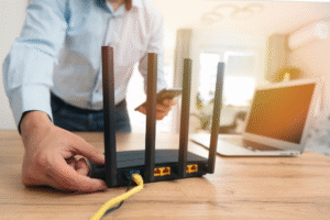 Person adjusting high-speed internet router for remote work setup with laptop in background