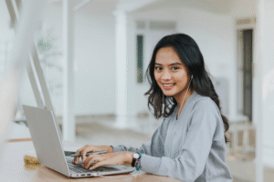 Professional Filipino candidate smiling confidently while working on laptop