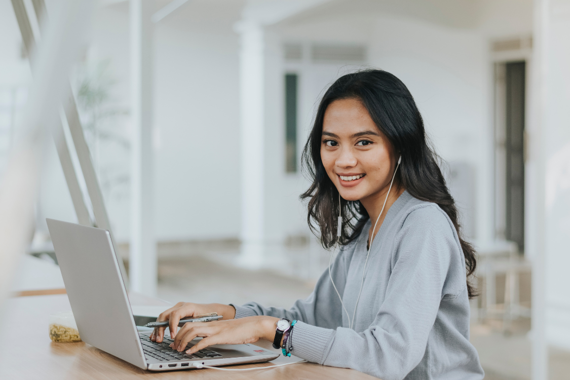Professional Filipino candidate smiling confidently while working on laptop