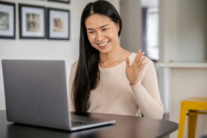 Filipino remote worker waving during a virtual meeting on a laptop