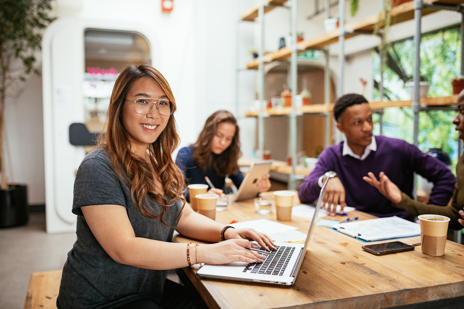 Smiling employee with colleagues in the background.