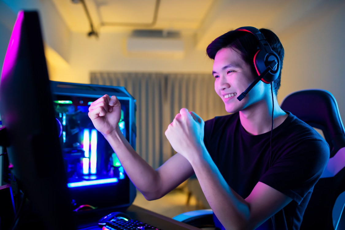 Man with headset celebrating a win during a virtual game on his computer